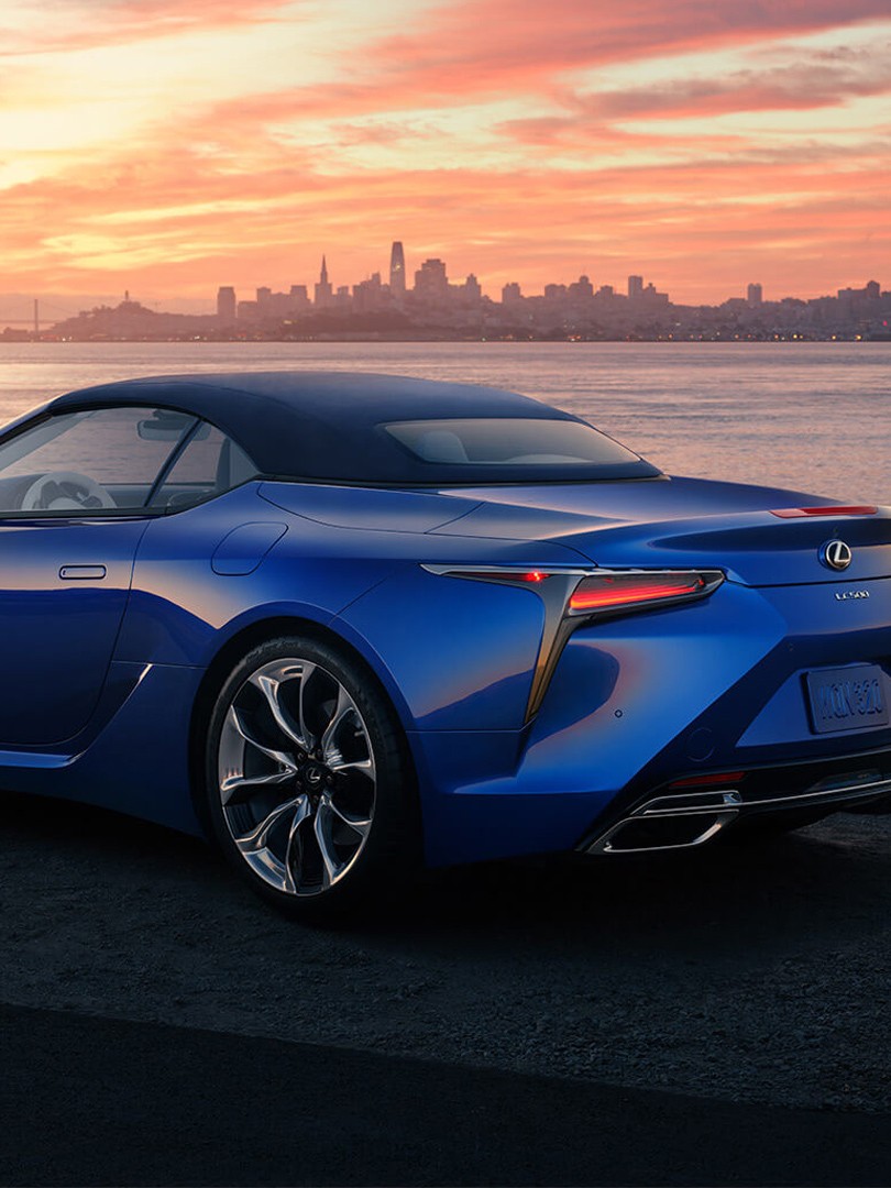 A woman walking away from a Lexus LC convertible