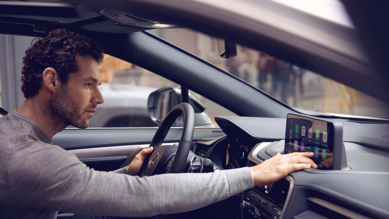 A man sat in a Lexus using the multimedia touch screen 