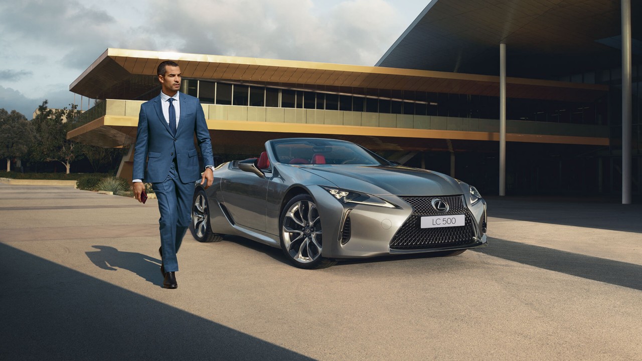 A man walking away from a parked Lexus LC Convertible 