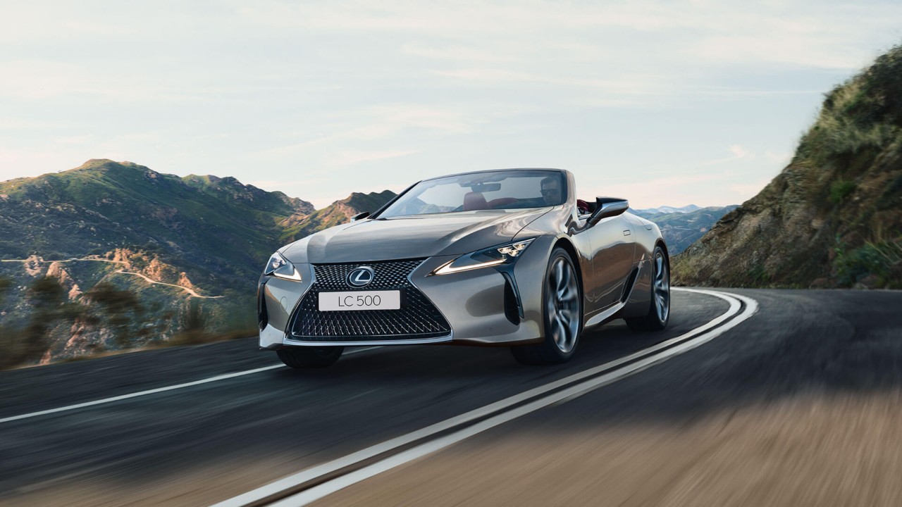 Lexus LC convertible driving around a corner in a mountainous location 
