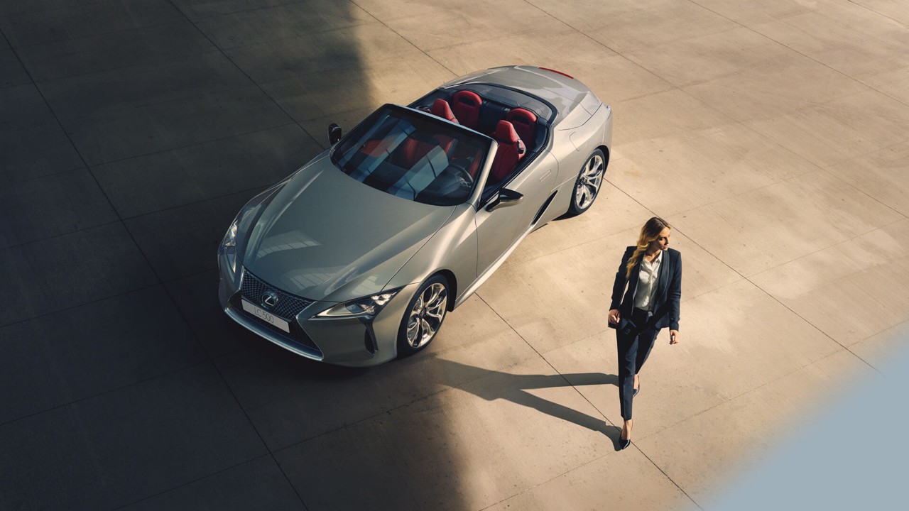 A woman walking away from a Lexus LC Convertible