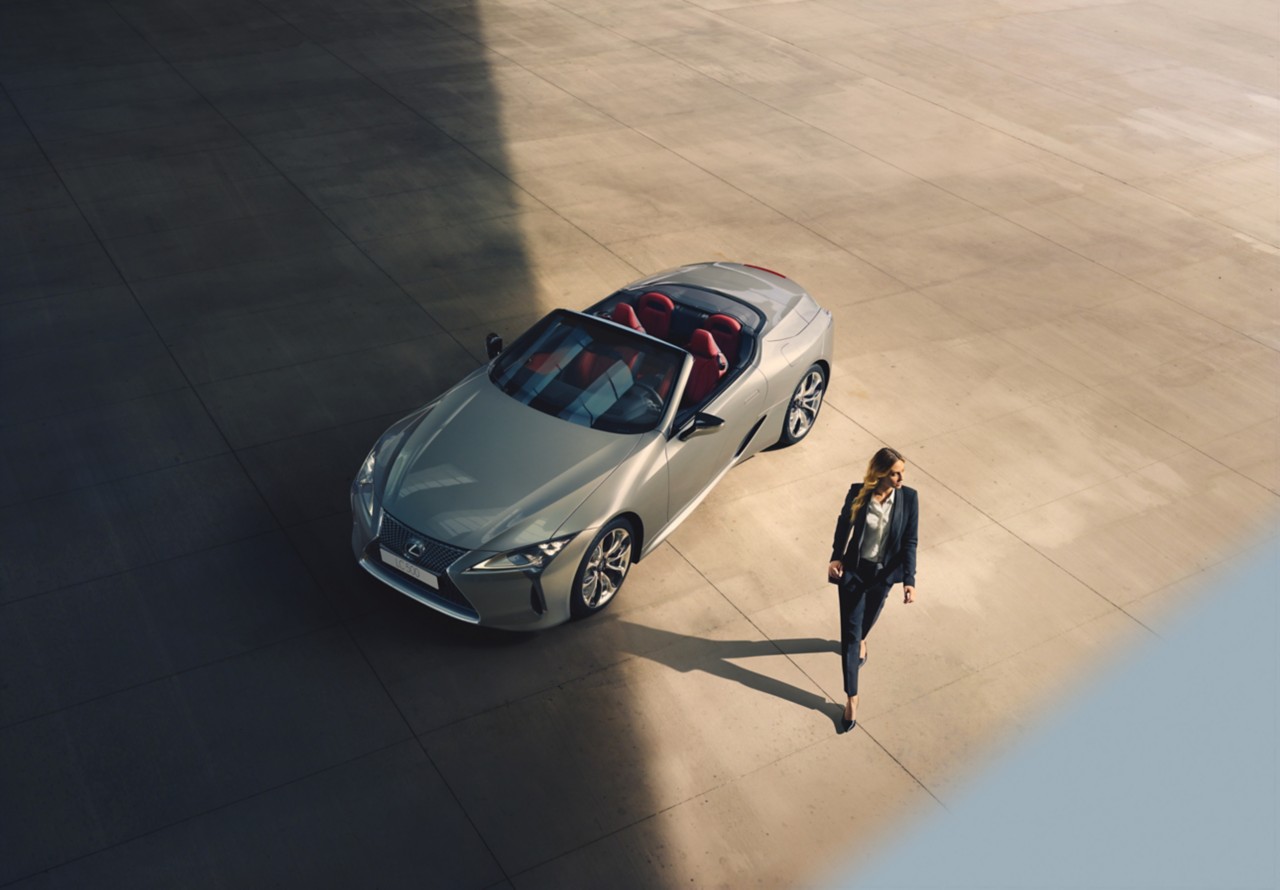 A woman walking away from a Lexus LC convertible