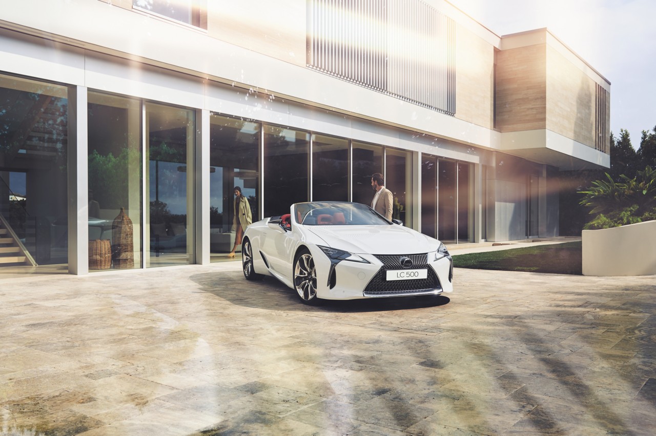A man standing next to a parked Lexus LC convertible