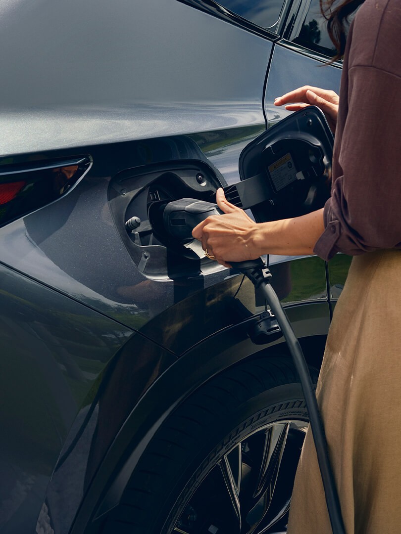 A woman plugging in a charger into a Lexus NX 